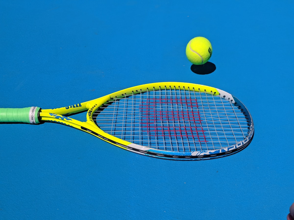 Tennis racquet and ball on blue hard court